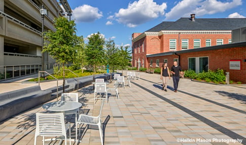 Two people talk to each other while walking through a plaza space at the Children’s National Research and Innovation Campus.