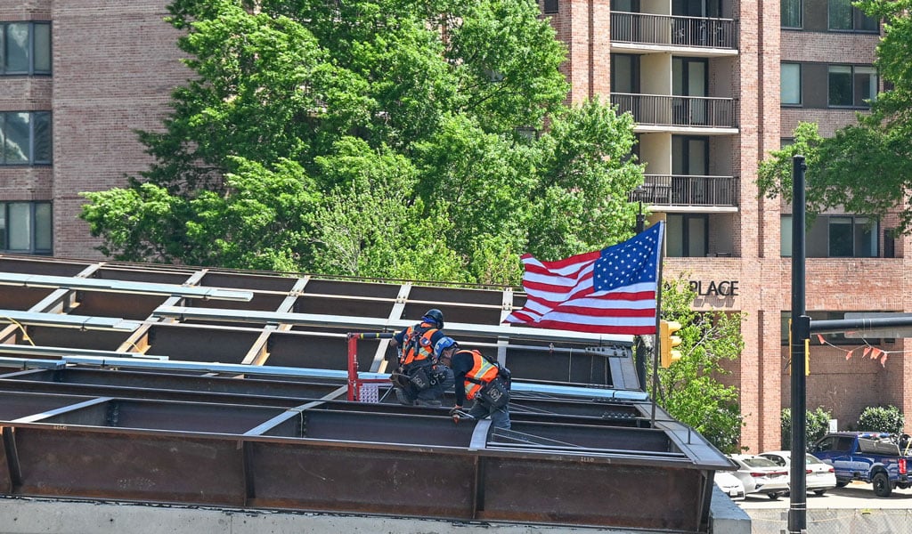 Construction workers place the signed beam in place at the CCEE.
