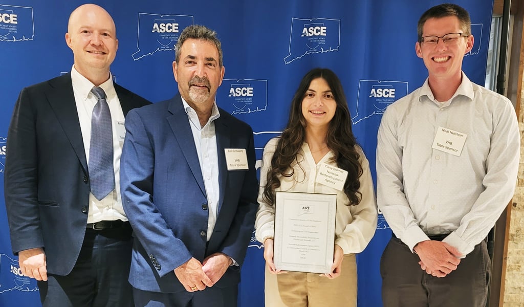 Four individuals posing in front of an ACEC banner, each wearing business attire and name tags.