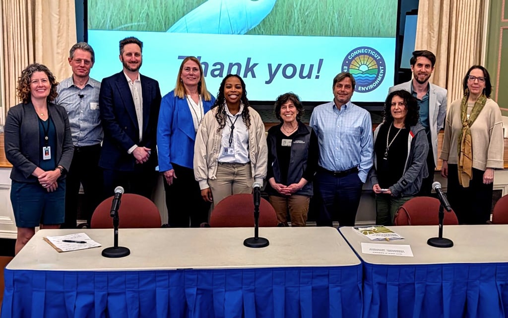 A group of ten people stands on a stage in front of a screen displaying an egret and the words "Thank you!" with a logo on the right side.  
