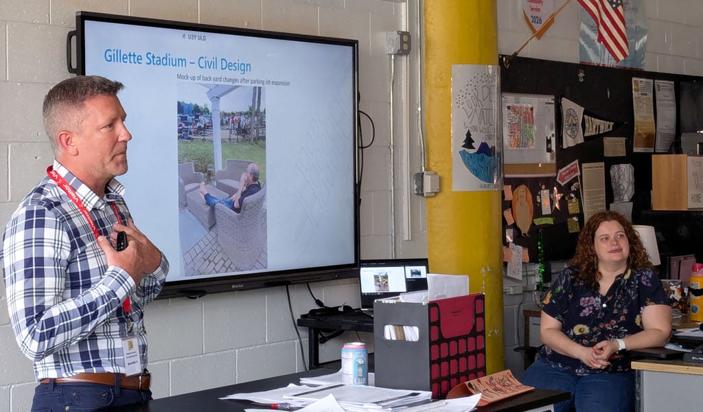 A man in blue checked shirt speaking to a teacher and other people outside the frame