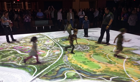 Children playing on a map of the park projected onto the floor during a public engagement meeting.
