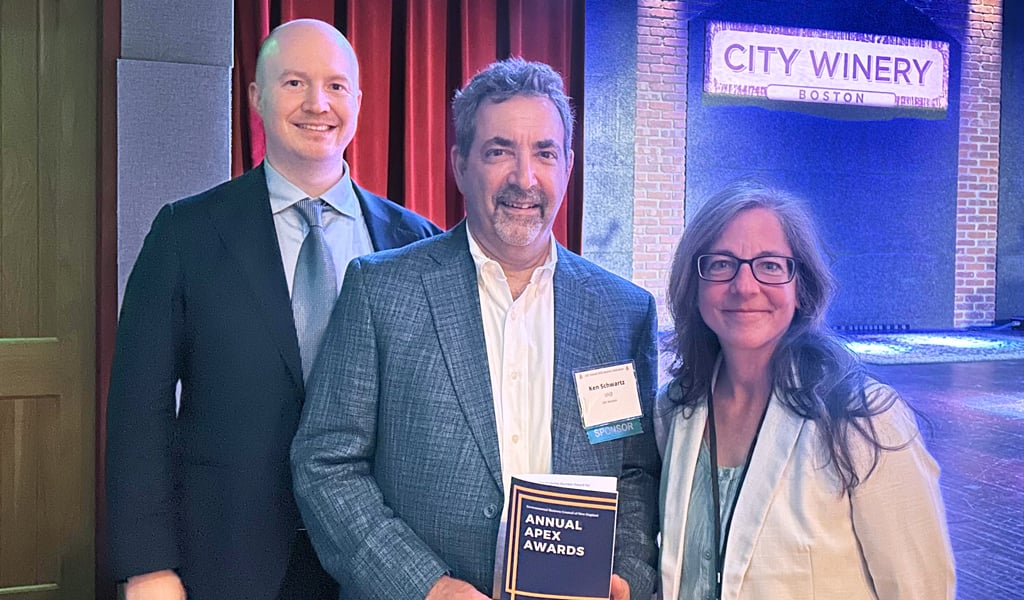 Three individuals stand on stage at City Winery, smiling with one person holding an 'EBC Annual Awards' program.