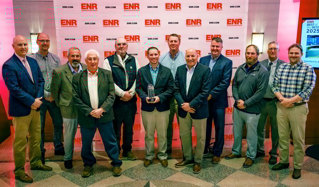 Group of people posing with an award in front of an "ENR" branded backdrop. The individuals are standing together, and one is holding a trophy. 