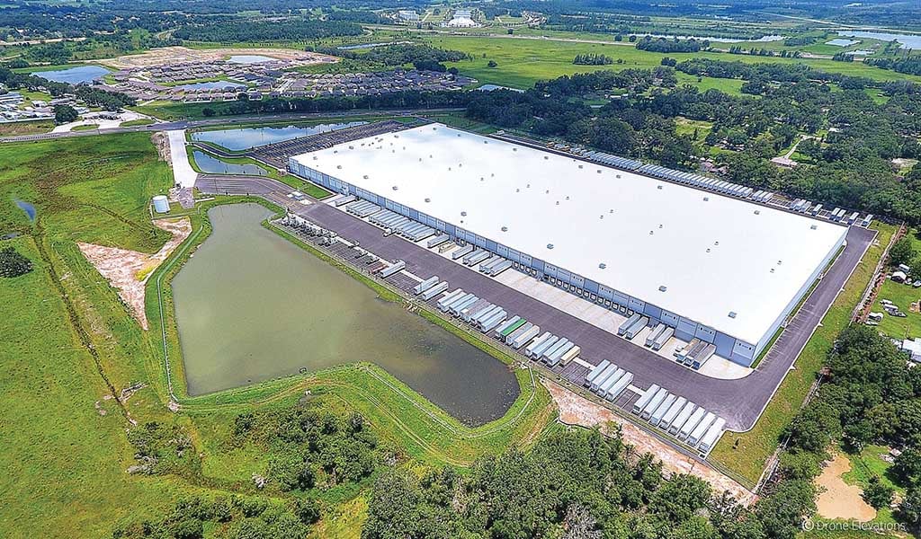 Aerial view of a large building with a stormwater pond. 