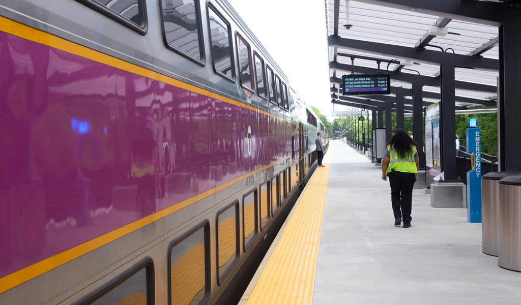 A Foxboro station platform sign, loading platform, and tracks.