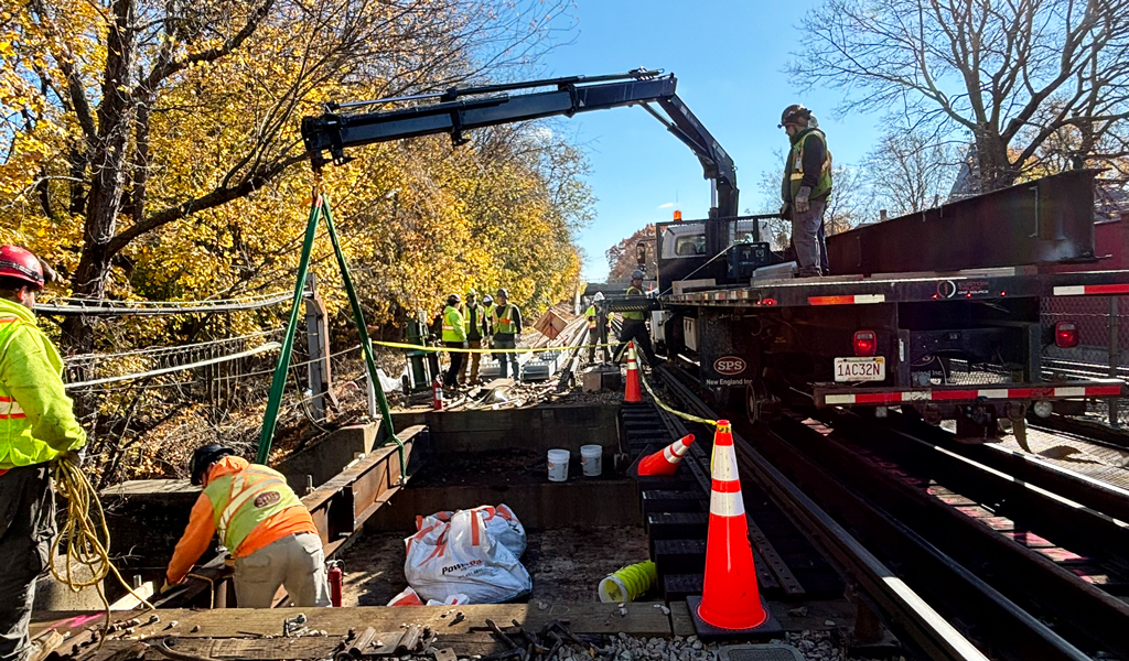 Workers on a railway track conducting maintenance and repairs using heavy machinery and tools.