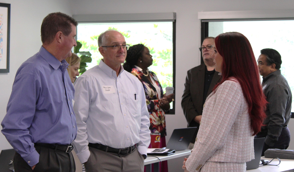 Workshop attendees standing in two small groups chatting and working together.