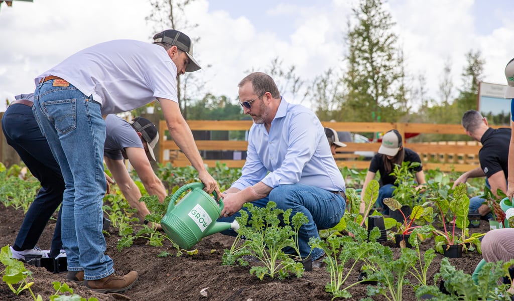 Jimmy Hoffman putting garden vegetables into a green bucket.