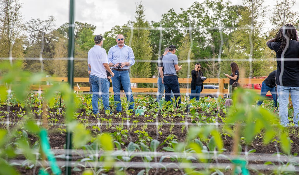 Jimmy Hoffman standing in a large vegetable garden talking to a guest.