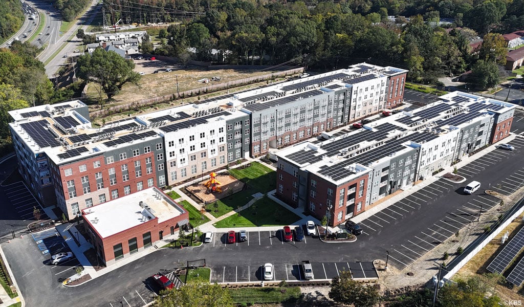 Aerial shots of an affordable multifamily housing project featuring solar panels, a playground, parking, and green spaces for residents.