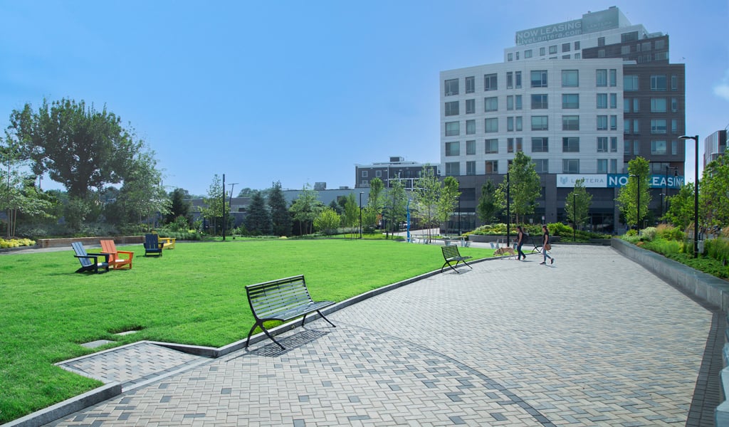Allston Yards Community Green, a one-acre park, during the daytime in the summer with blue skies. 