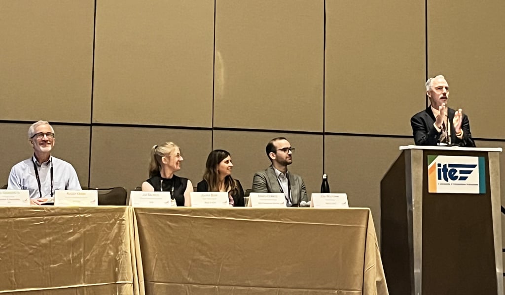 Four panelists and a speaker at a podium with the ITE logo, during a conference session.