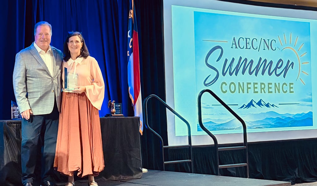Jenny Fleming stands on stage holding her award with Michael Holder, former ACEC/NC President.  