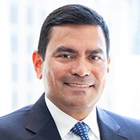 A person in a dark blue suit and polka-dot tie.