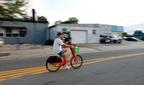 Man riding a Lime rental bike at dusk.  