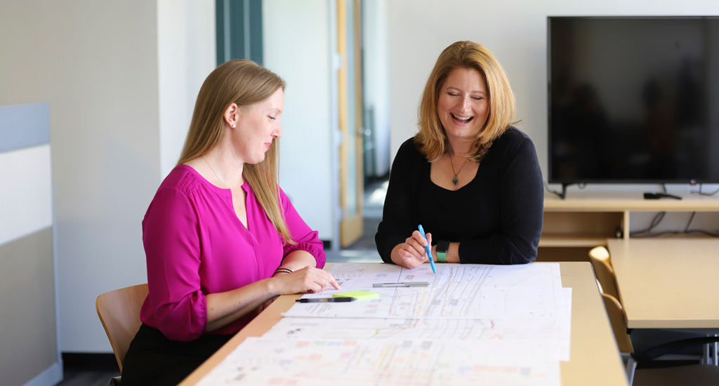 Lee Farmer and Meghan Powell sitting at a table reviewing engineering plans.