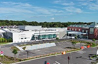 Hospital building with an adjacent parking lot, surrounded by roads and landscaped areas.