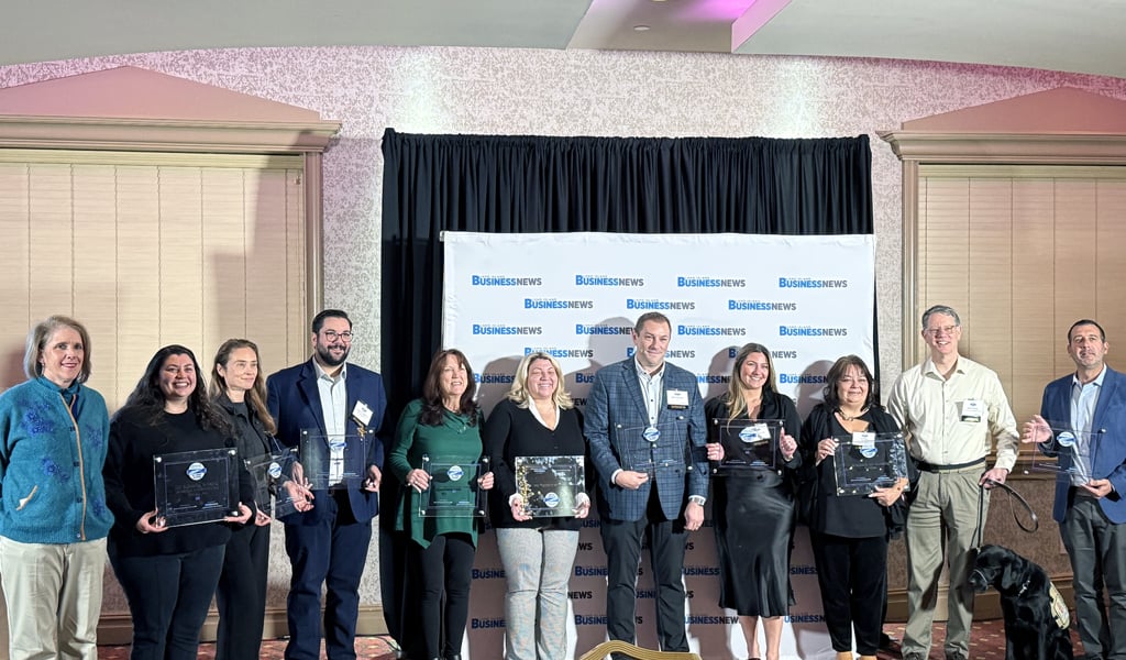 Award winners holding their awards in front of backdrop.