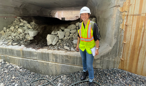 CREST Intern, Lily Liu stands at a construction site wearing project gear.