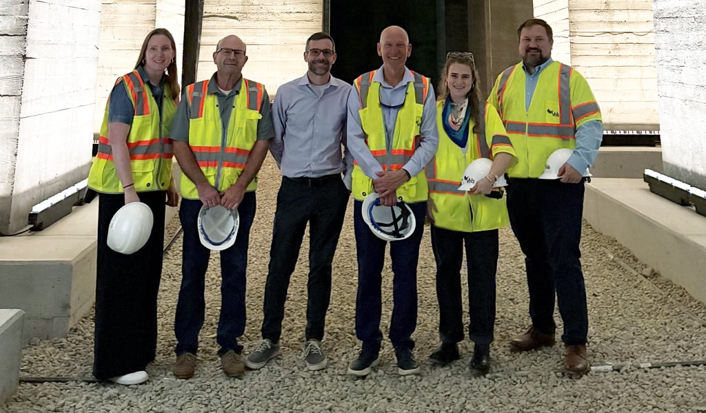Group of six VHBers standing in the undercroft next to the illuminated concrete foundations.