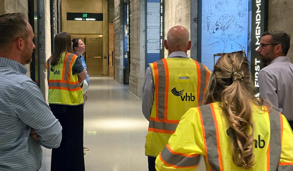 The VHB team walking through the museum in high visibility vests looking at glass exhibit cases.