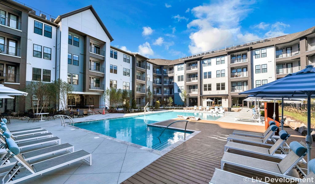 Lounge chairs and apartment buildings surround the courtyard pool.  