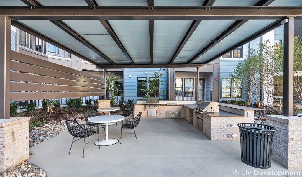 A covered grilling space with tables and chairs.   
