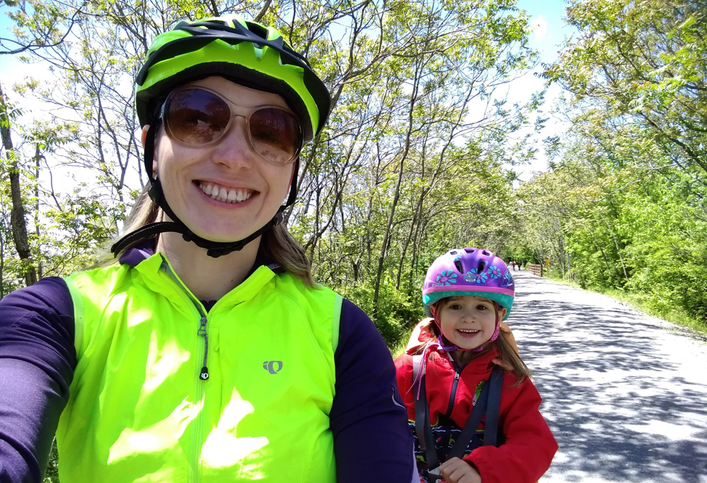 Lyuba and her daughter smile at the camera during a bike ride.
