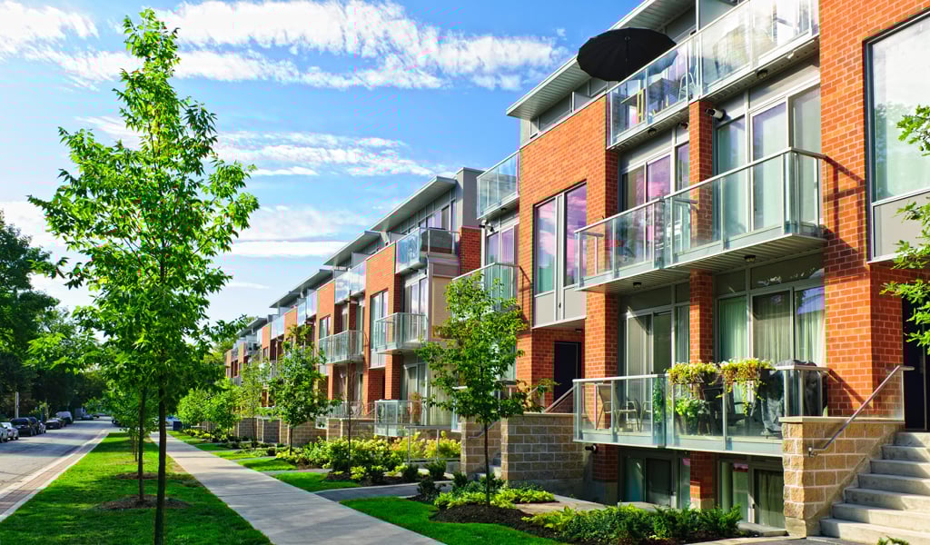 An apartment complex with greenery along the sidewalks.