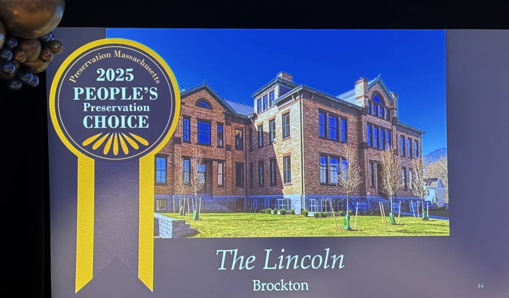 Attendees at an event with a presentation slide showing Brockton's The Lincoln School, winner of the 2025 People's Preservation Choice award.