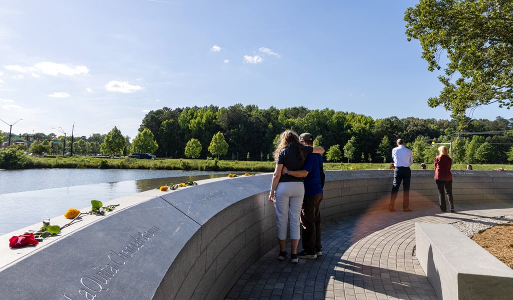 A couple hugging each other while looking at the memorial.