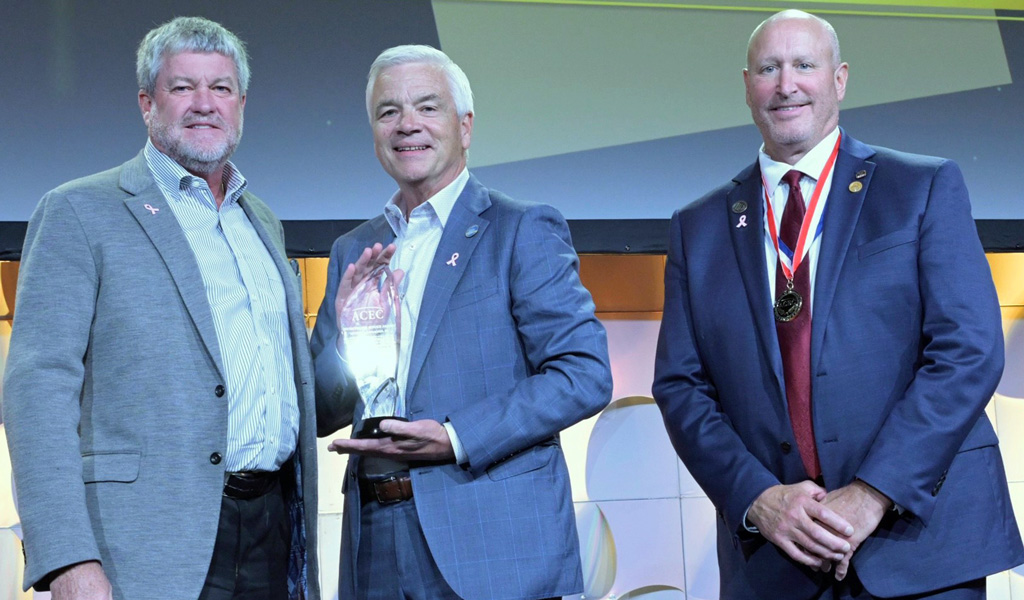 Three men smiling on stage.