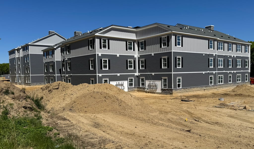 New multifamily residential building under construction on a cleared site with surrounding trees.