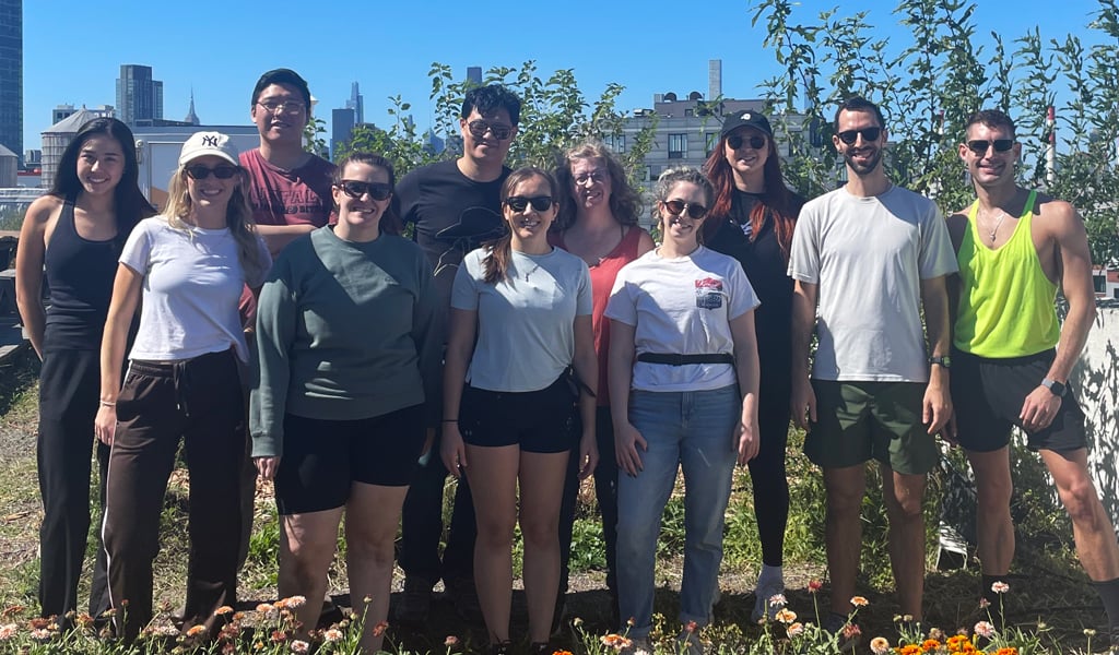 The Green Team gathers in front of rows of flowers on a rooftop farm in Long Island City.