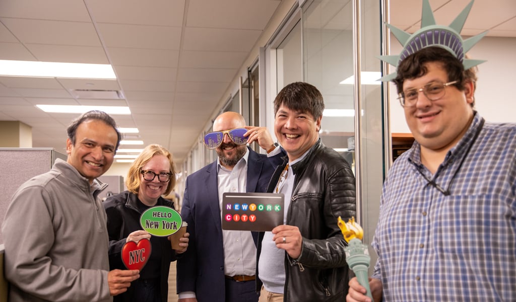 Team members hold New York-themed photo props during Generational Company Day celebrations.