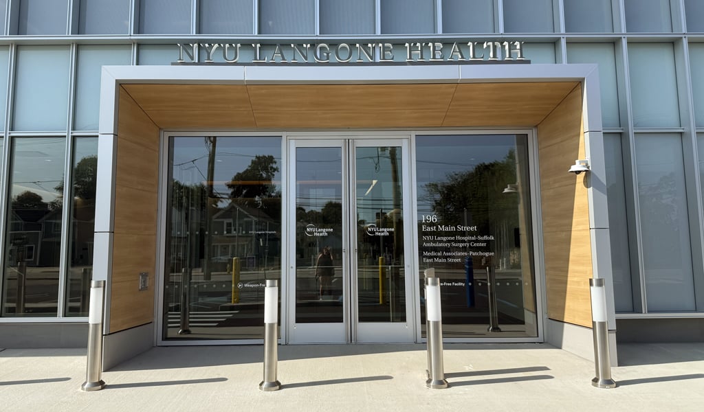 Close-up of NYU Langone Health Ambulatory Care Center glass entrance with address signage and bollards.