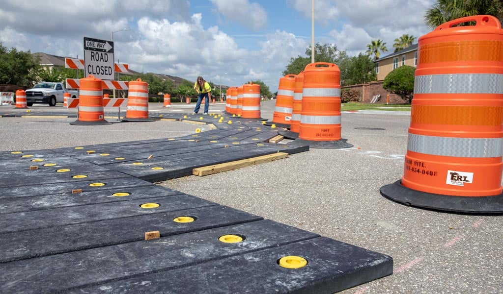 A construction worker wearing a vest working on a road.
