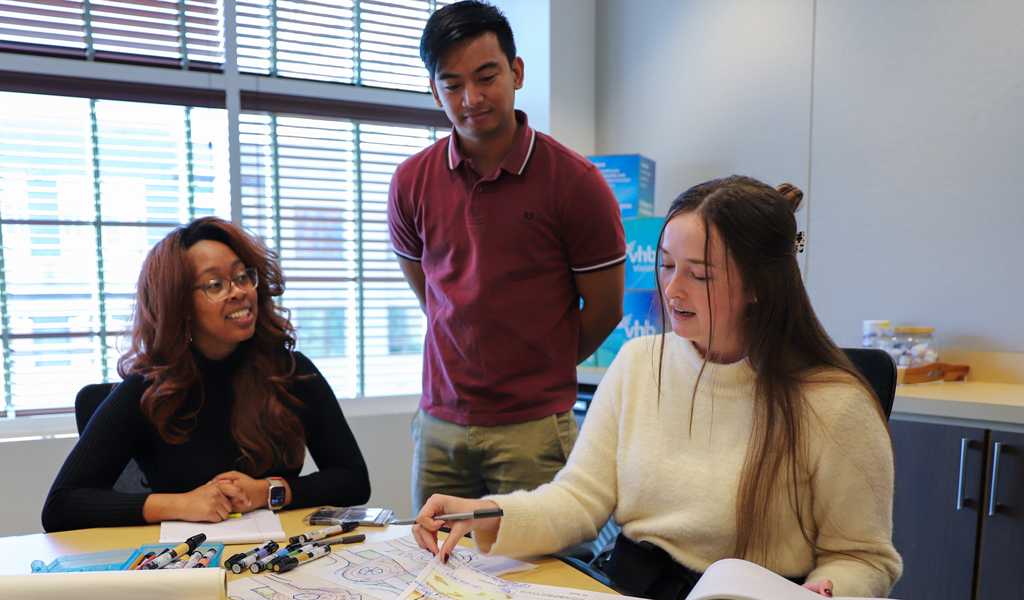 Three young people working at a desk.