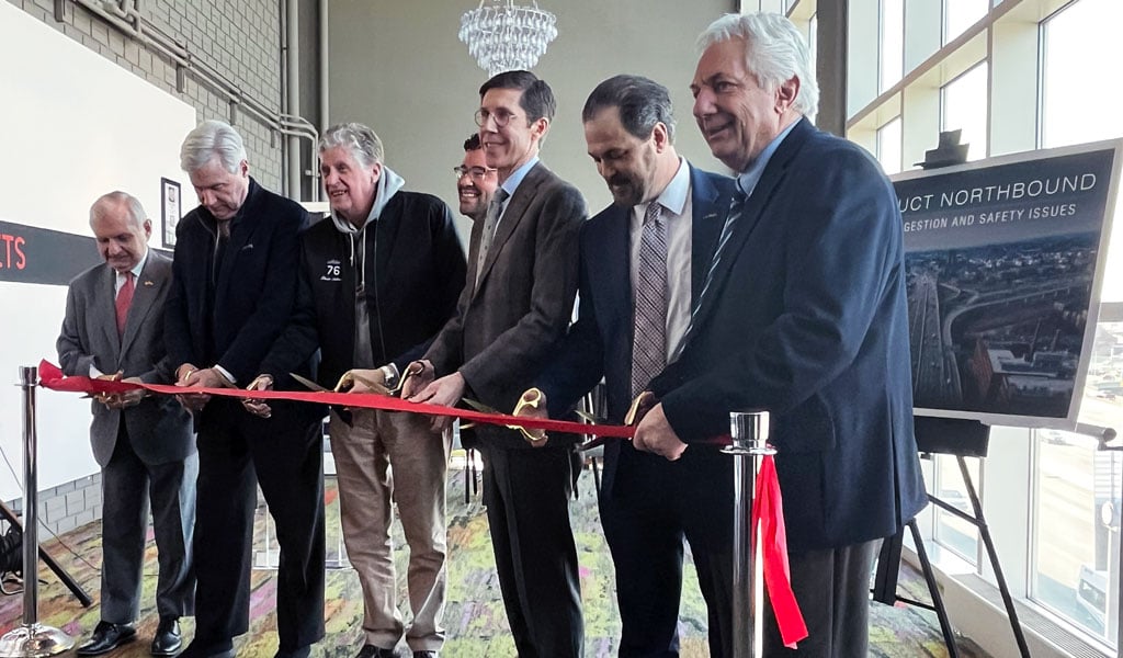 A group of men cutting a red ribbon.
