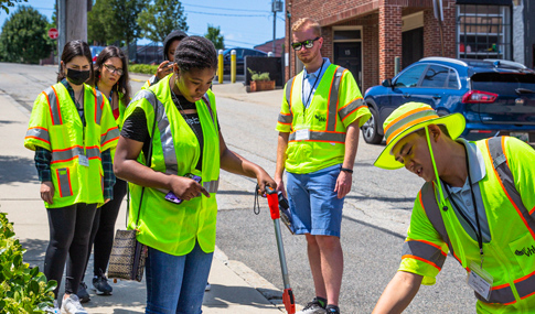 A group of students outside measuring a sidewalk.