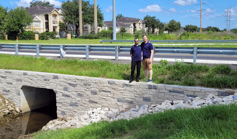Two people are standing at a stormwater culvert on Raleigh Street.