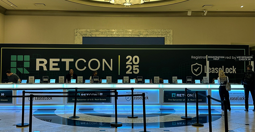 Registration area for RETCON 2025 event, featuring a series of check-in counters under a large, modern chandelier, with logos of sponsors like LeaseLock visible.