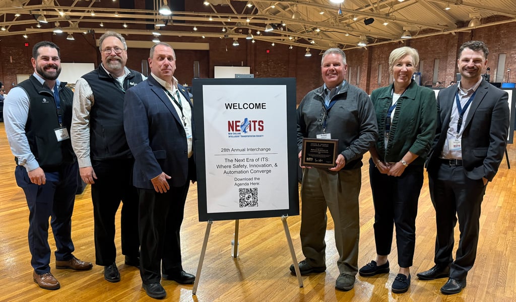 Six people around an NEITS welcome sign, with Ron Hartman holding his ITS award.
