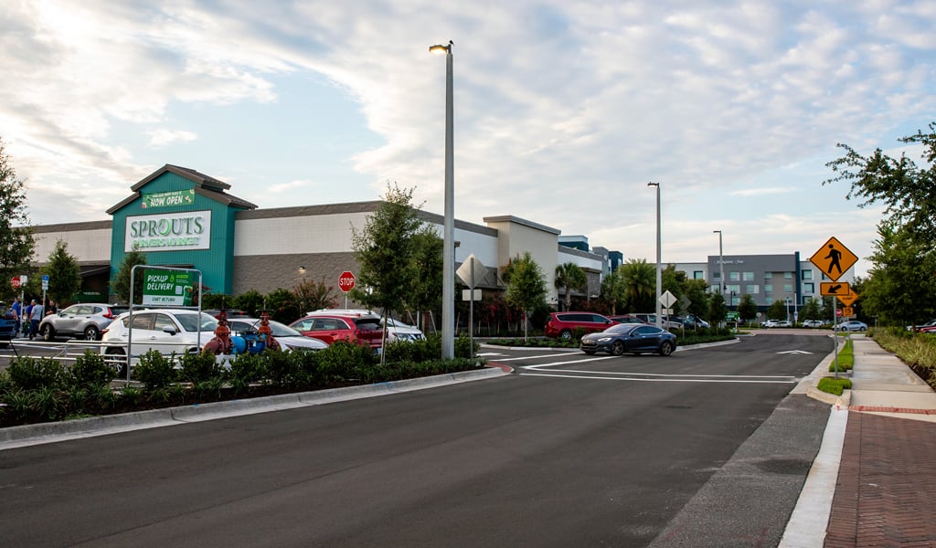 Large Sprouts building and its new parking lot featuring green landscaping and brick paver crosswalks.