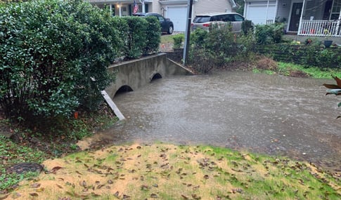 Endwall structure filling with flood waters in residential front yard.