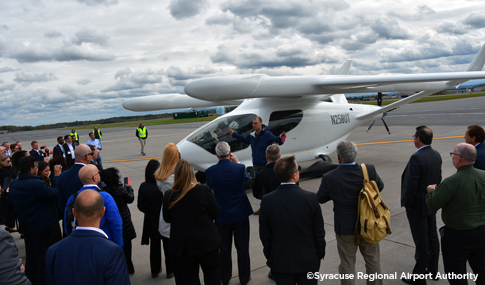 A group of people standing around a white AAM aircraft.