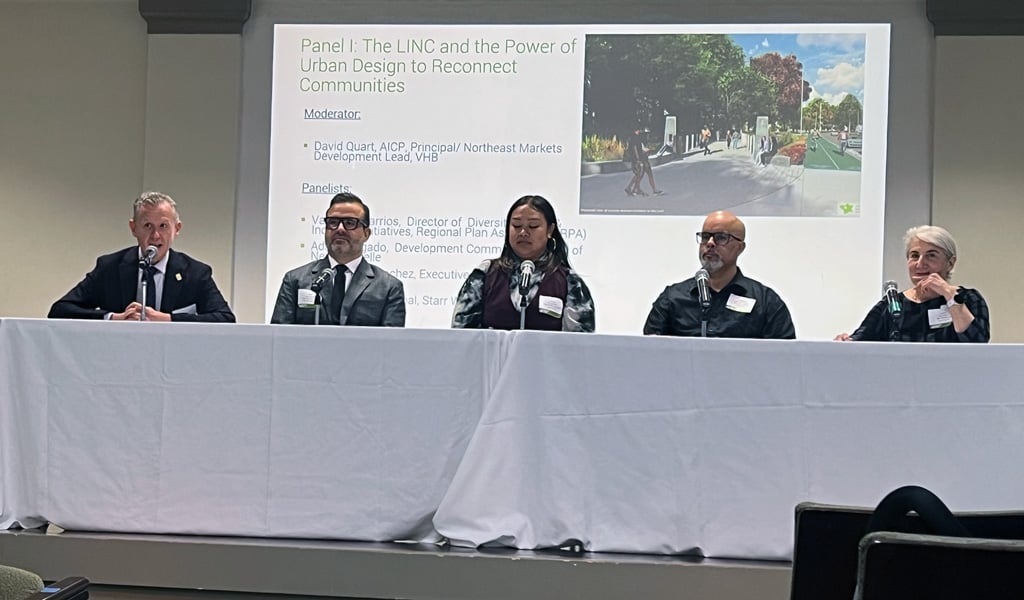 David Quart sitting at a table with panelists in front of the LINC presentation. 