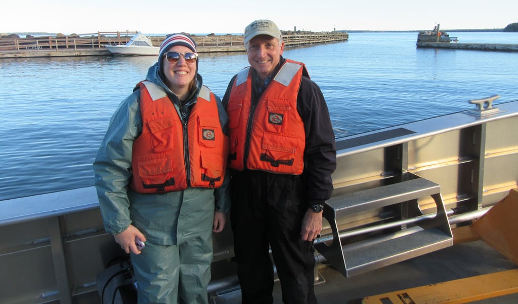 Erin and Tim smiling in orange life vests while on a boat.