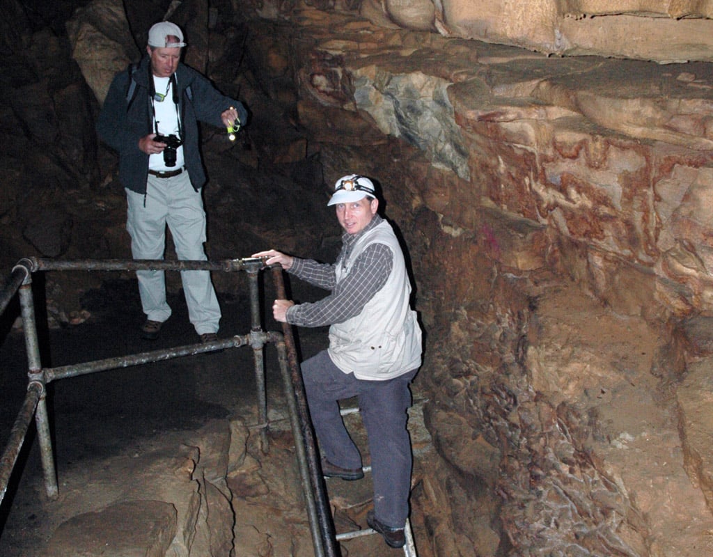 Tim climbing up a ladder in the dark with a headlamp in Mammoth Cave National Park.